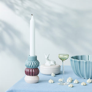 Lysestake fra Dottis Nordic Design med en hvit kronelys plassert i en kombinasjon av keramiske deler i mørk, pudder og aubergine, dekorativt arrangert med tilbehør.