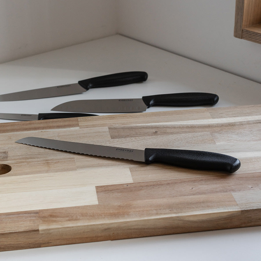 Everyday Cut brødkniv 20 cm plassert på en trebenk med flere kjøkkenkniver, perfekt for daglig bruk i kjøkkenet.