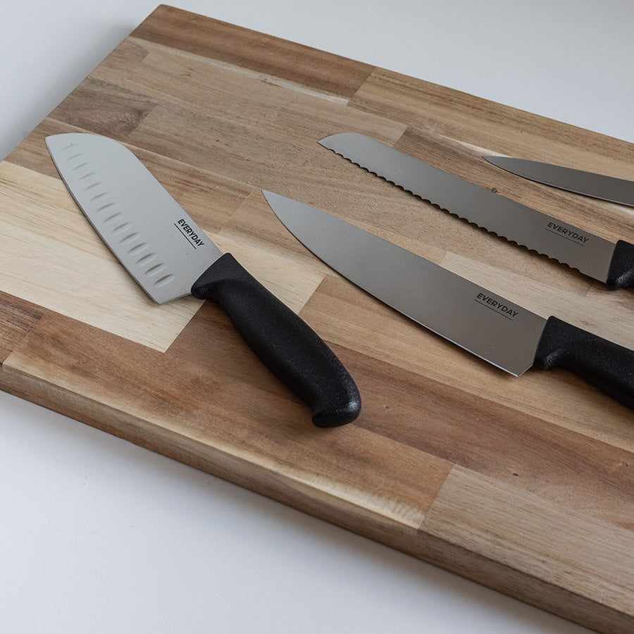 Utvalg av Everyday kniver inkludert en santokukniv på en skjærefjøl, ideell for effektiv matlaging.