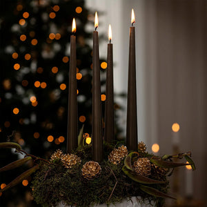 Flora Danica julepynt dekorert med 18 karat gullbelagte furukongler, plassert på et bord med grønne detaljer og lys.