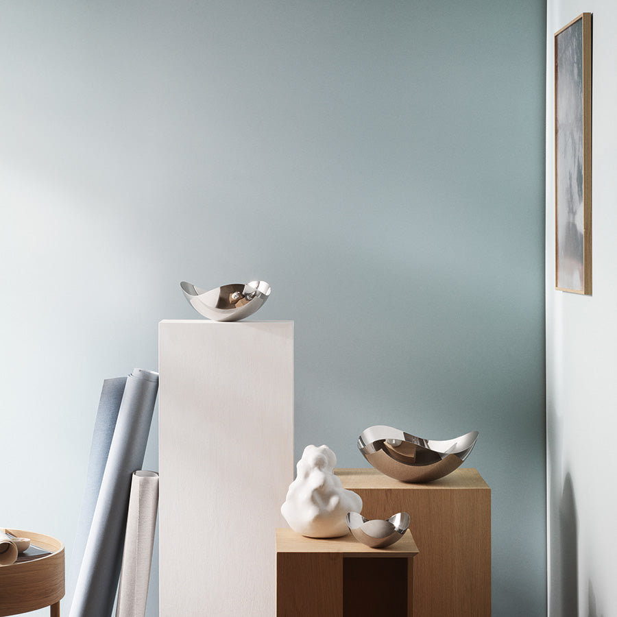 Stilren setting med flere blanke serveringskåler i rustfritt stål, plassert på moderne møbler for dekorativt formål.
