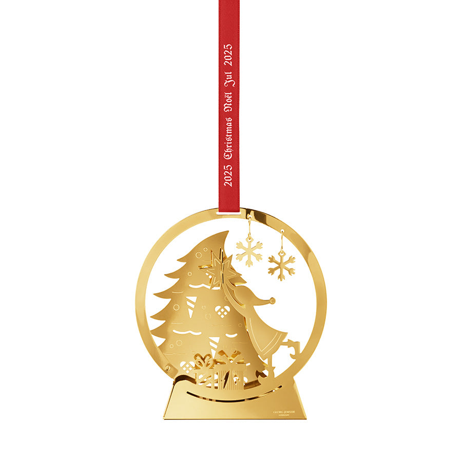 Georg Jensen CC 2025 Juleuro Snøkule i 18 karat gullbelagt design, med en liten jente som plasserer stjernen på toppen av et juletre, levert med rødt silkebånd.