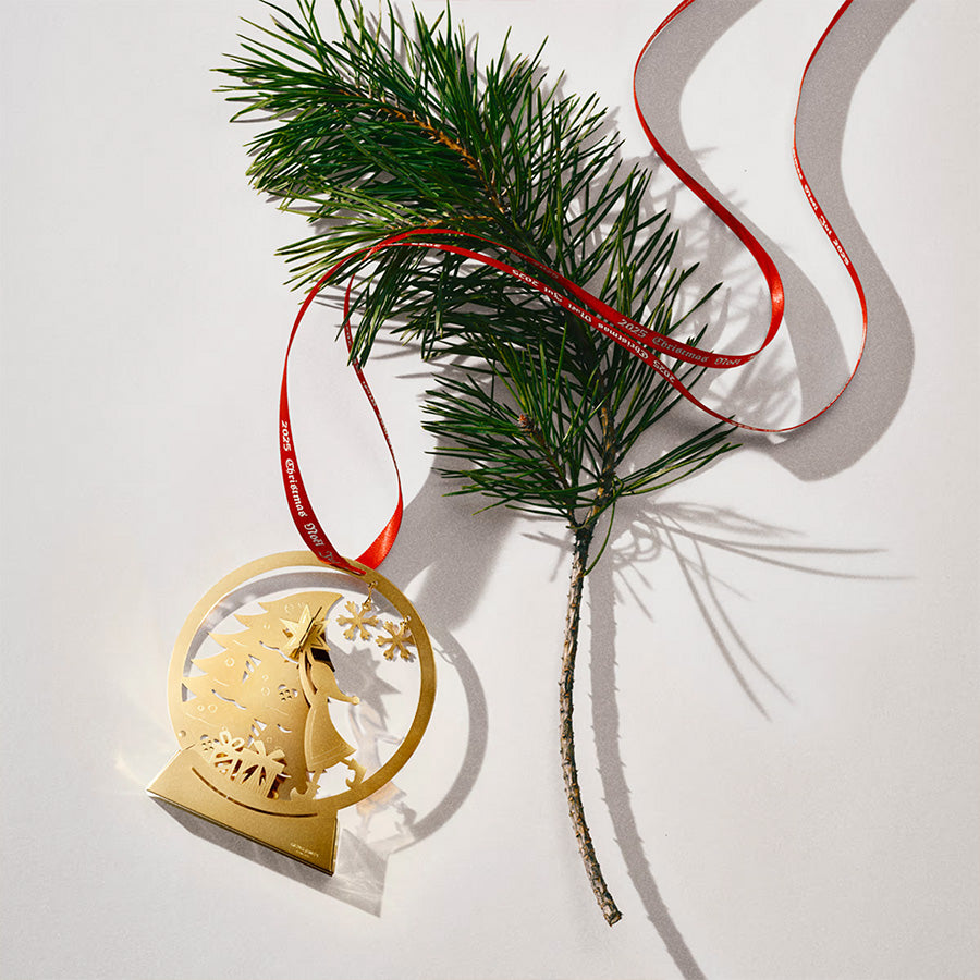 Georg Jensen CC 2025 Snøkule Juleuro i 18 kt gull, fremhevet med granbar og rødt silkebånd, perfekt til juledekorasjon.