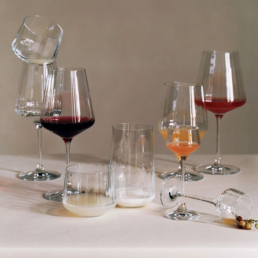 Variasjon av rødvinsglass i forskjellige størrelser og stiler, inkludert rødvinsglass, på et elegant bord med drikke.
