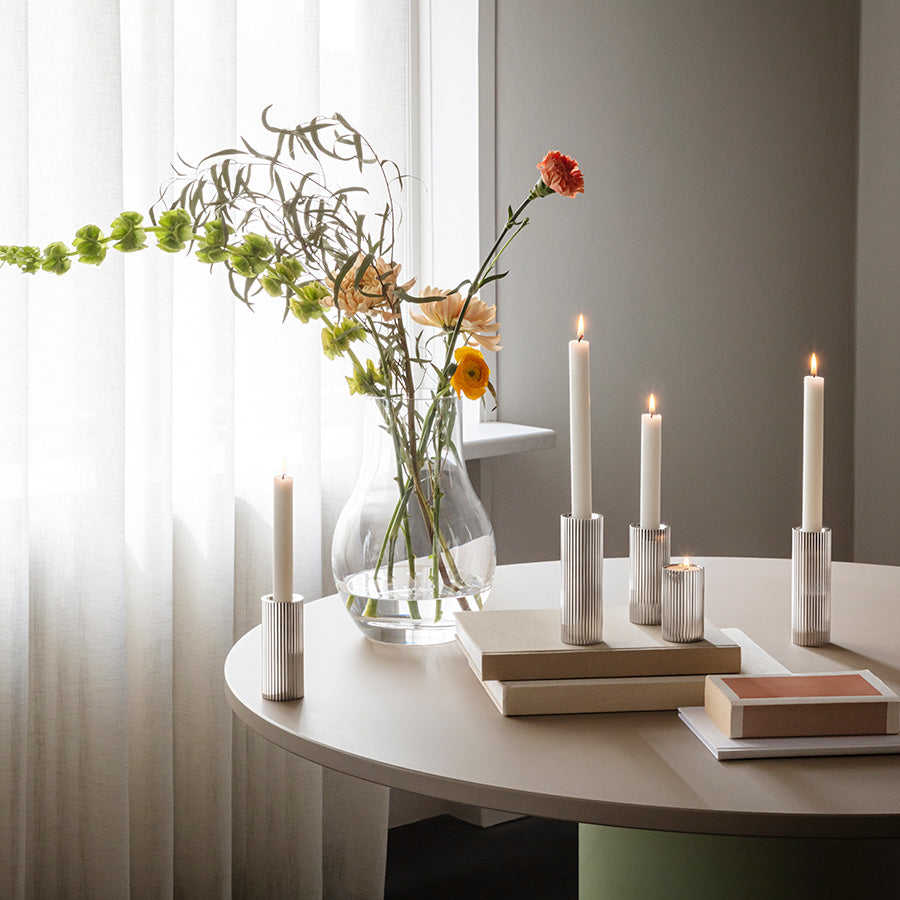 Dekorativ styling med Georg Jensen Bernadotte telysholdere/lysestaker i sett på tre, med tente lys ved vinduskarm og blomster i vase