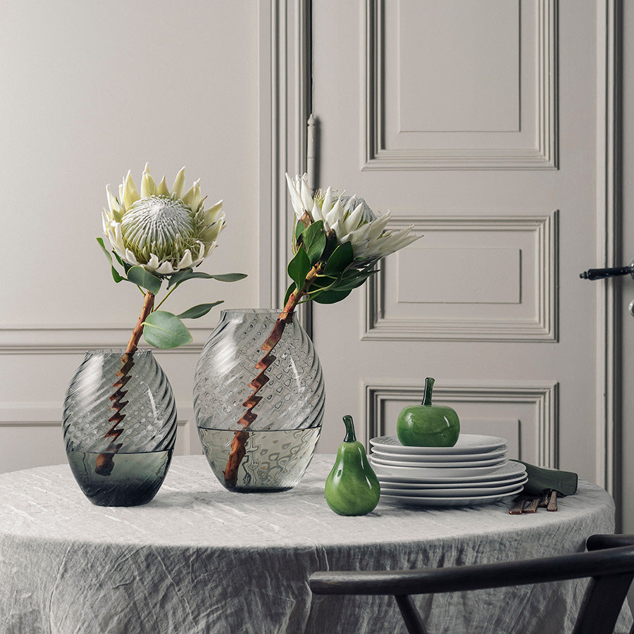 Røkgrå Nora vase fra Hadeland Glassverk med blomster på et elegant dekket bord