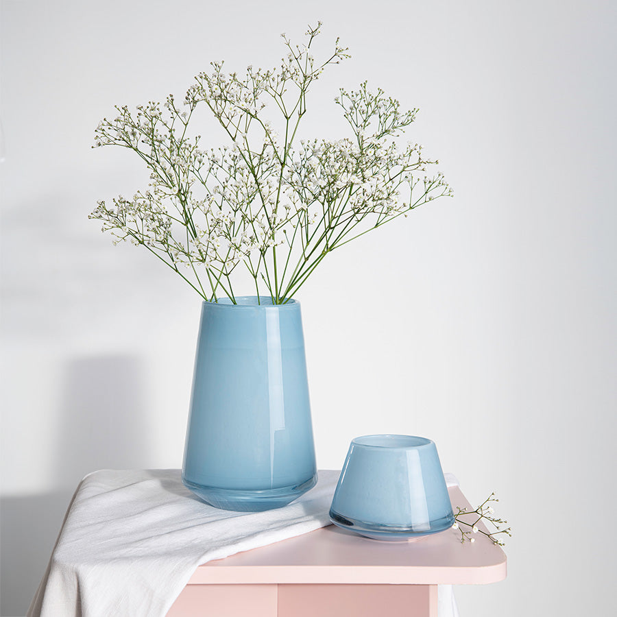 Lyslykt plassert med blomster i en lys blå vase, viser hvordan lyslykten kan brukes som dekorativ detalj i hjemmet.