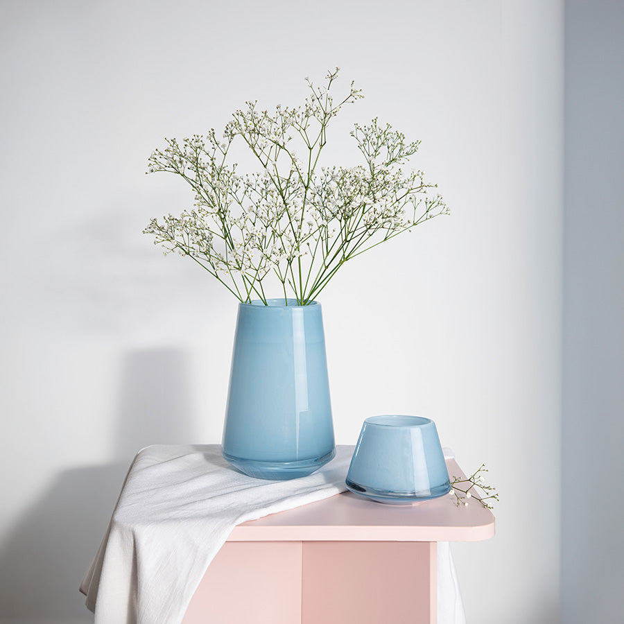 Hadeland Glassverk Dugg Vase 20cm Lys Blå - vasen med blomster på et bord, viser hvordan den kombinert med en mindre vase skaper et harmonisk og stilrent interiør.