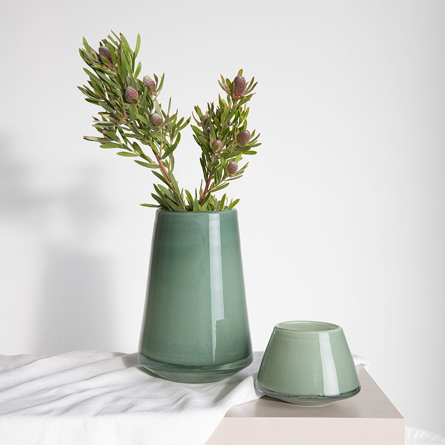 Stor grønn vase med blomster, kombinert med en mindre vase i matchende farge, ideell for stilfull interiørdekorasjon.