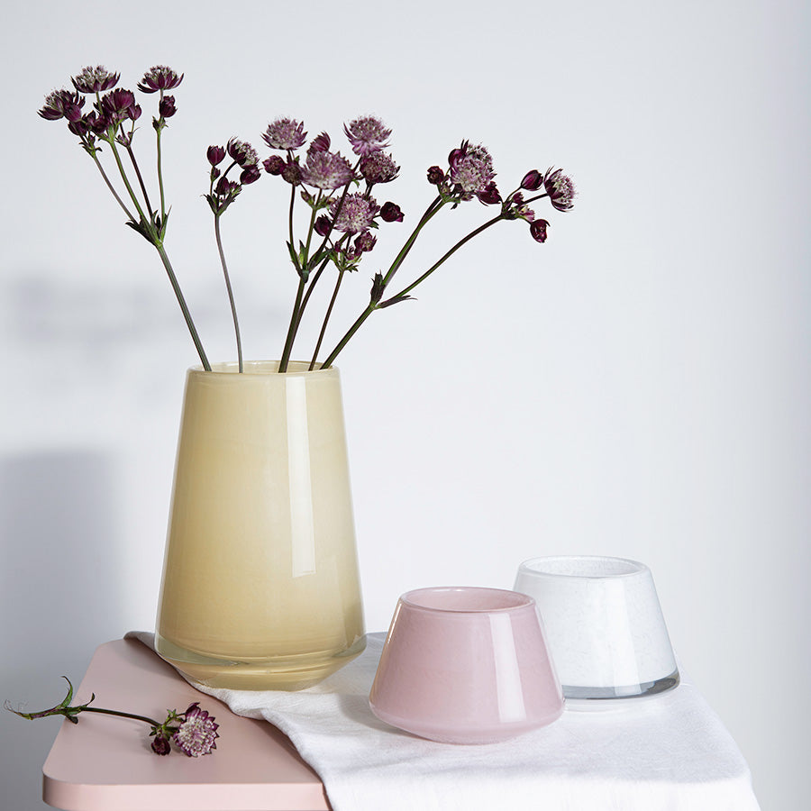 Hadeland Glassverk Dugg vase i gull med blomster, satt sammen med minimalistiske interiørdetaljer og moderne design.