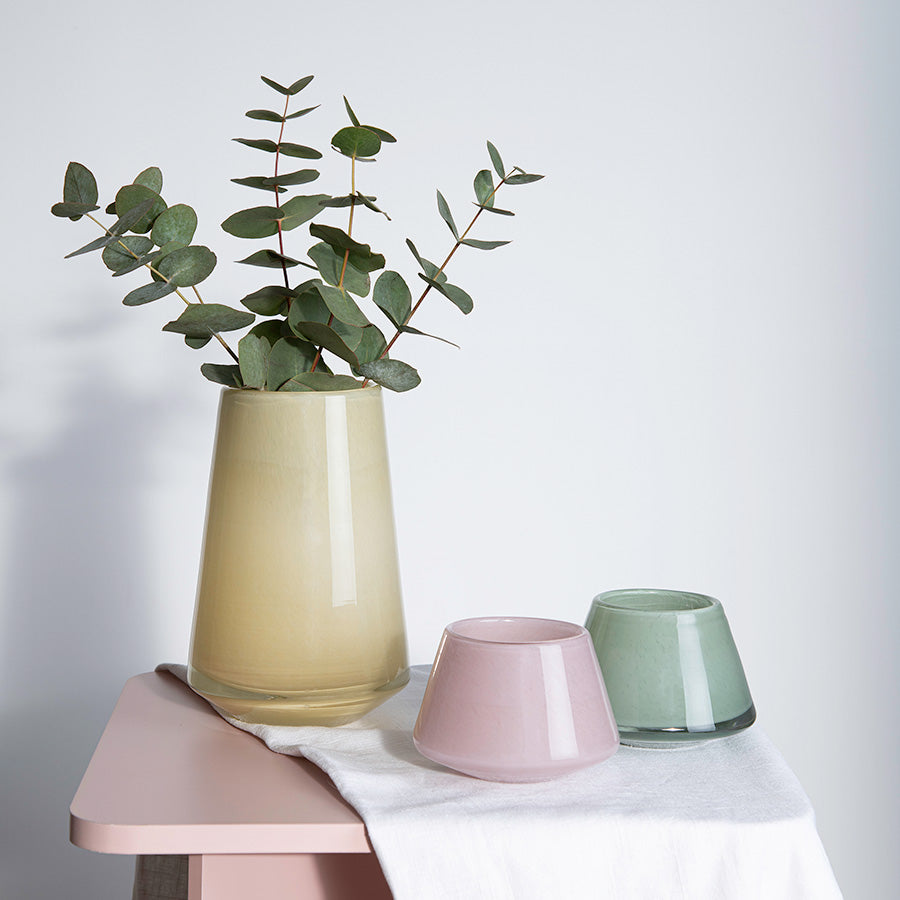 Hadeland Glassverk Dugg vase i 20 cm høyde med eukalyptus og fargede småvaser, presentert på et moderne bord med nøytral bakgrunn.