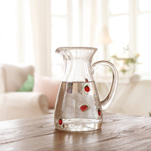 Klar glassmugge fra Hadeland Glassverk med jordbær, plassert på et trebord i solfylte omgivelser.