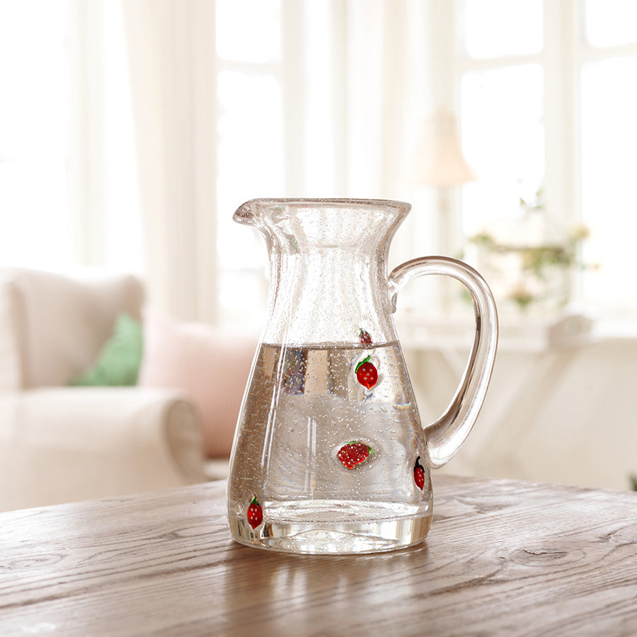 Klar glassmugge fra Hadeland Glassverk med jordbær, plassert på et trebord i solfylte omgivelser.