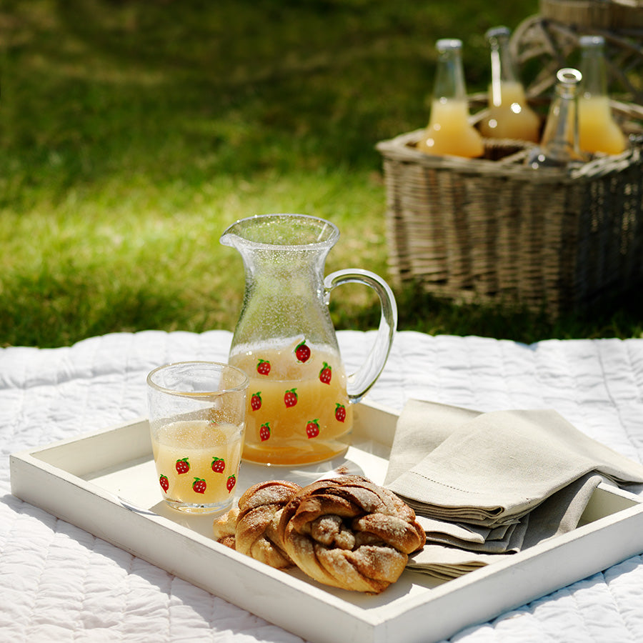 Hadeland Jordbær glass servert med en mugge på en picnic i parken, skaper en koselig stemning for utendørs sammenkomster.