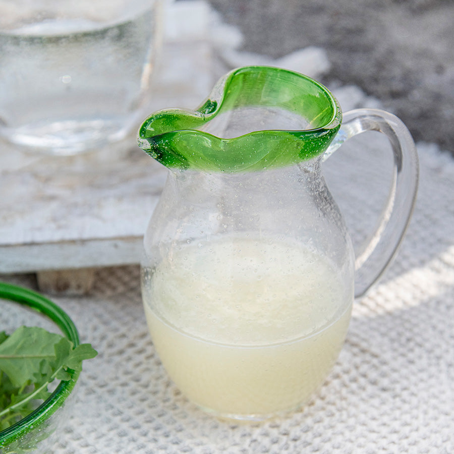Hadeland Glassverk Sommereng mugge med grønn kant, fylt med lemonade, en vakker detalj til borddekorasjonen.