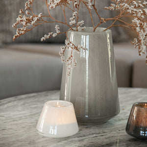 Off-white Dugg telysholder fra Hadeland Glassverk med tent telys på et stilfullt marmorbord