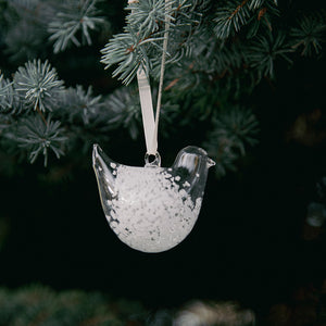 Hvit, spettet glassfigur formet som en turteldue henger i juletreet