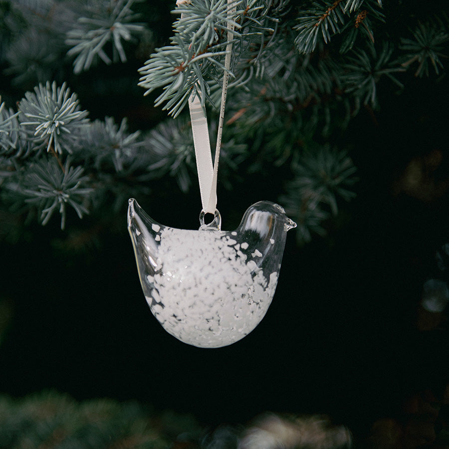 Hvit, spettet glassfigur formet som en turteldue henger i juletreet