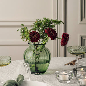 Grønn Ella vase fra Hadeland Glassverk med blomster som borddekorasjon på et stilfullt dekket spisebord