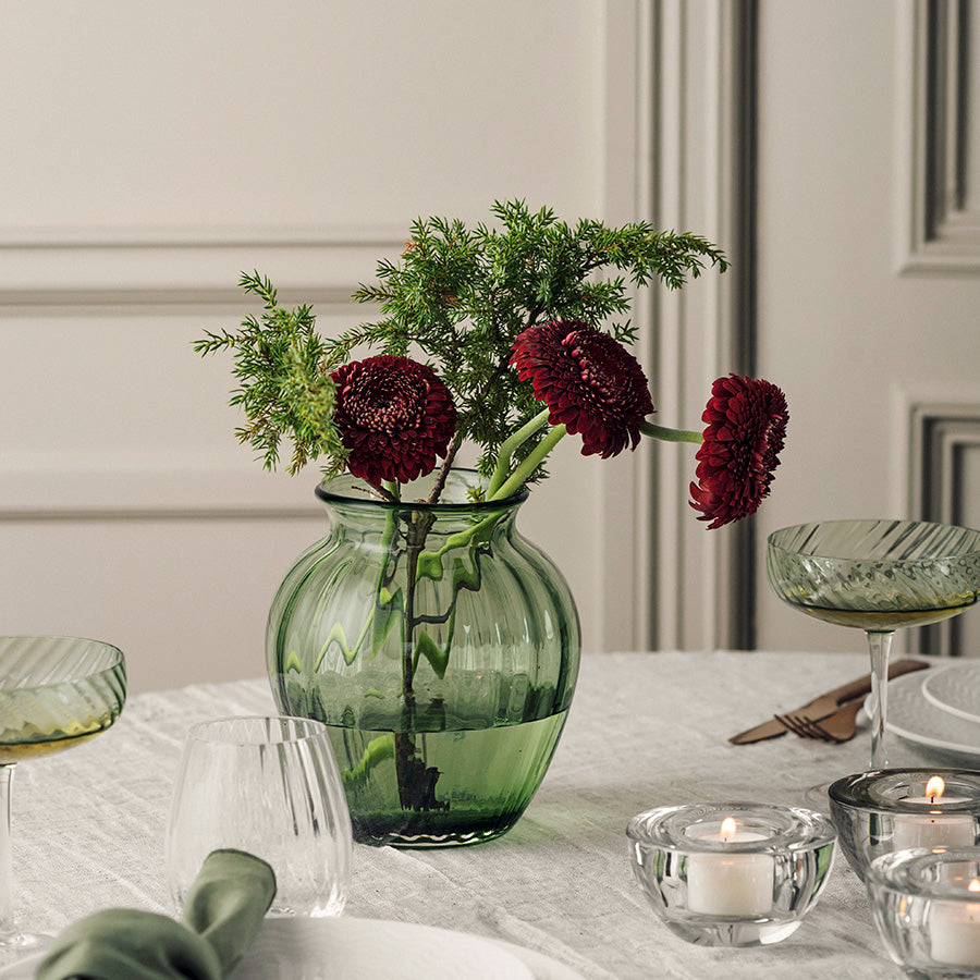 Grønn Ella vase fra Hadeland Glassverk med blomster som borddekorasjon på et stilfullt dekket spisebord