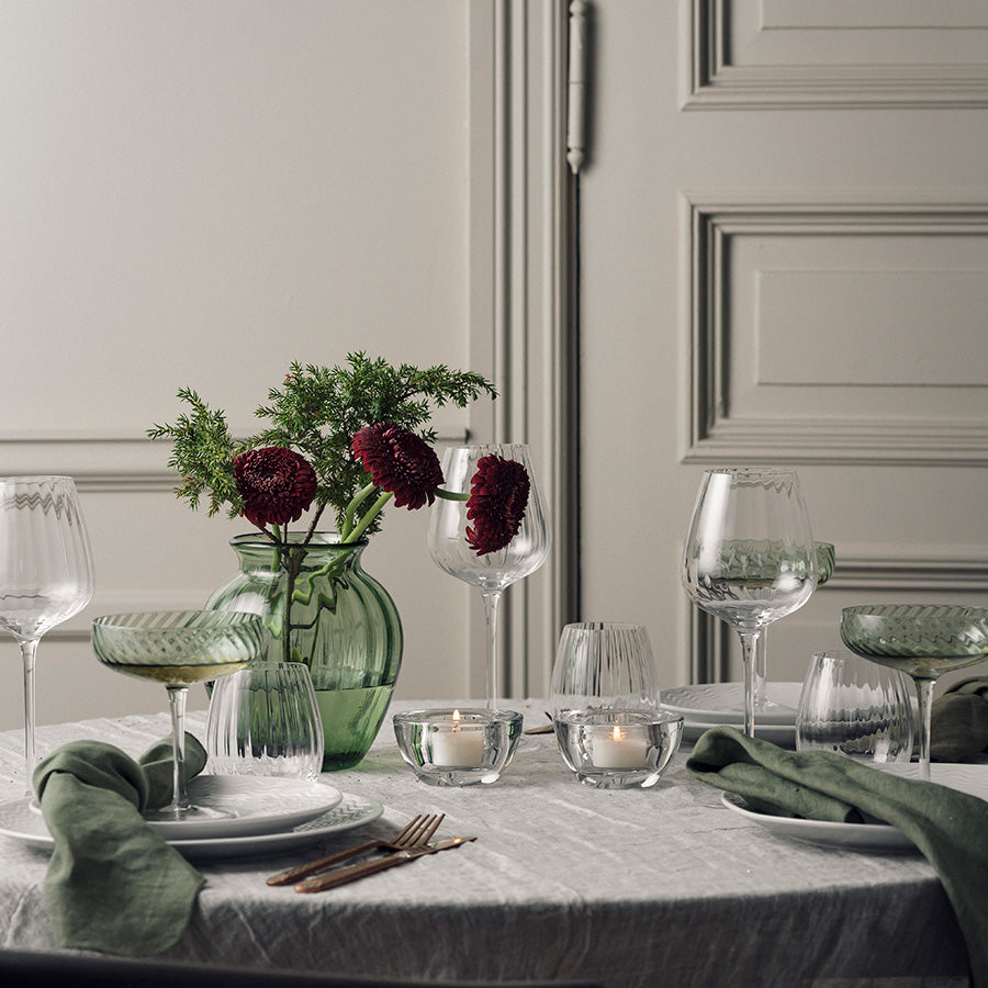Hadeland Glassverk Ella vase i grønt glass med blomster, dekorert på et elegant spisebord med lys og glass