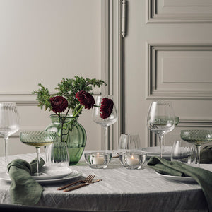 Hadeland Glassverk Ella vase i grønt glass med blomster, dekorert på et elegant spisebord med lys og glass