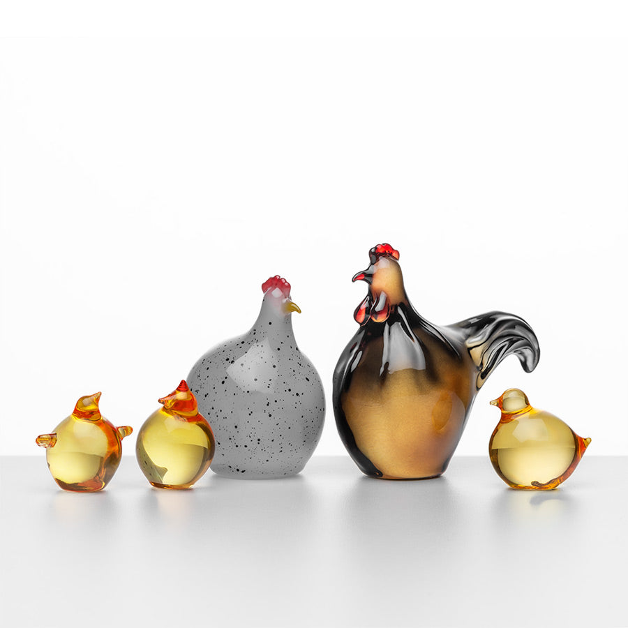 Samling av Hadeland Glassverk Hane og kyllinger i glass. Den store hanen er munnblåst, sammen med tre mindre glasskyllinger i gult og grått, ideelt for påskepynting.