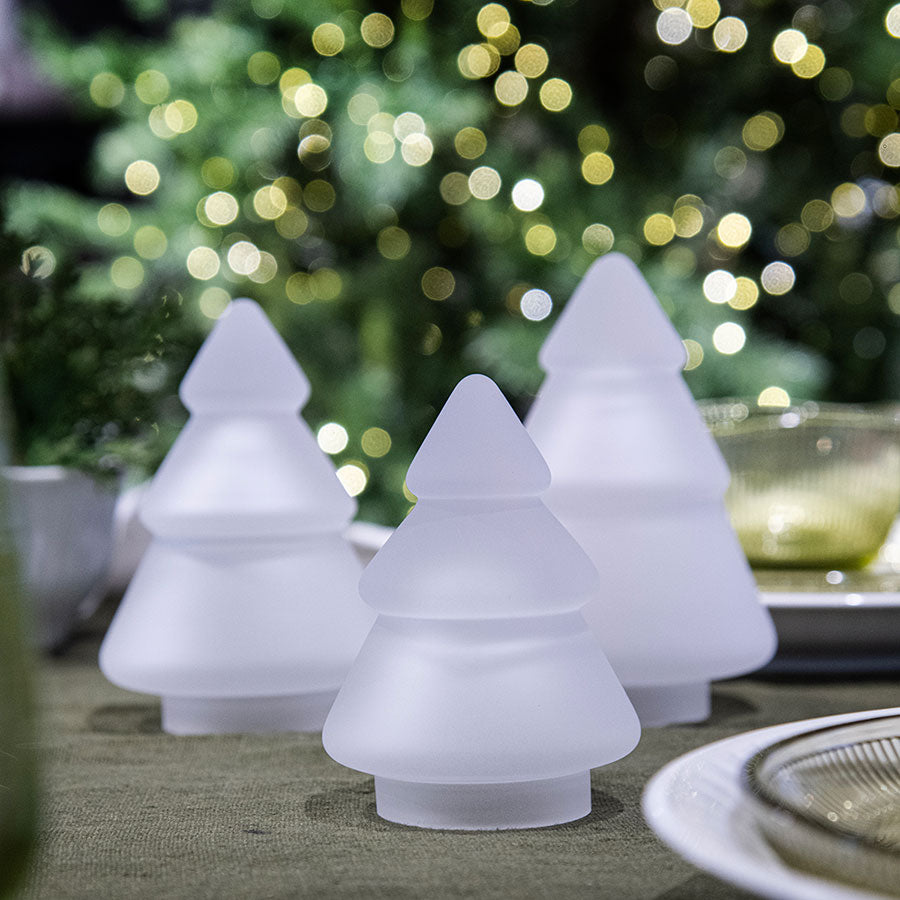 Tre frosted glass juletre fra Hadeland Glassverk, samling av juletre med bakgrunn av lys og juledekorasjoner.