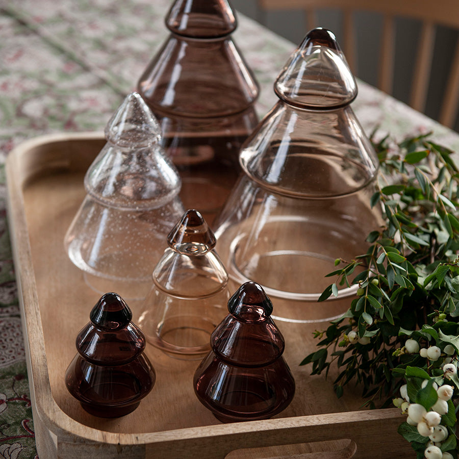 Dekorative Gran krukker i klart og brunt glass samlet på et fat, perfekt til julepynt og oppbevaring