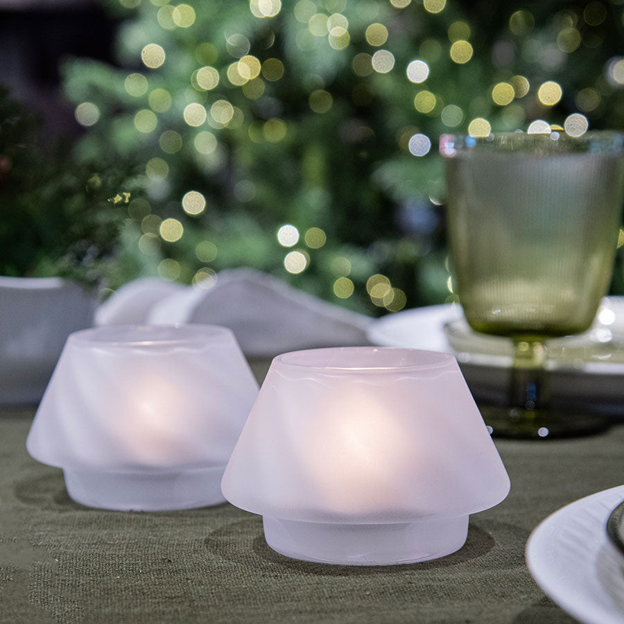 Frostede lyslykter fra Hadeland Glassverk plassert på et dekket bord, med dekorativ bakgrunn og mykt lys som skaper julestemning.
