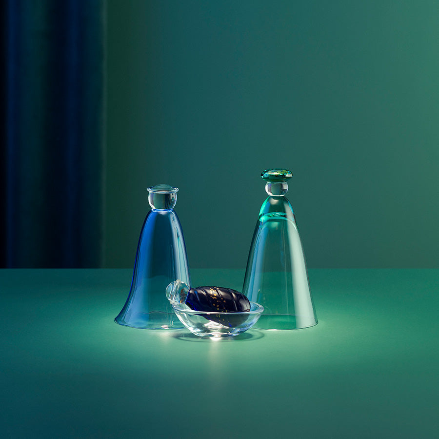 Stemningsfull julekrybbe fra Hadeland Glassverk i blått, grønt og klart glass, belyst på et bord.
