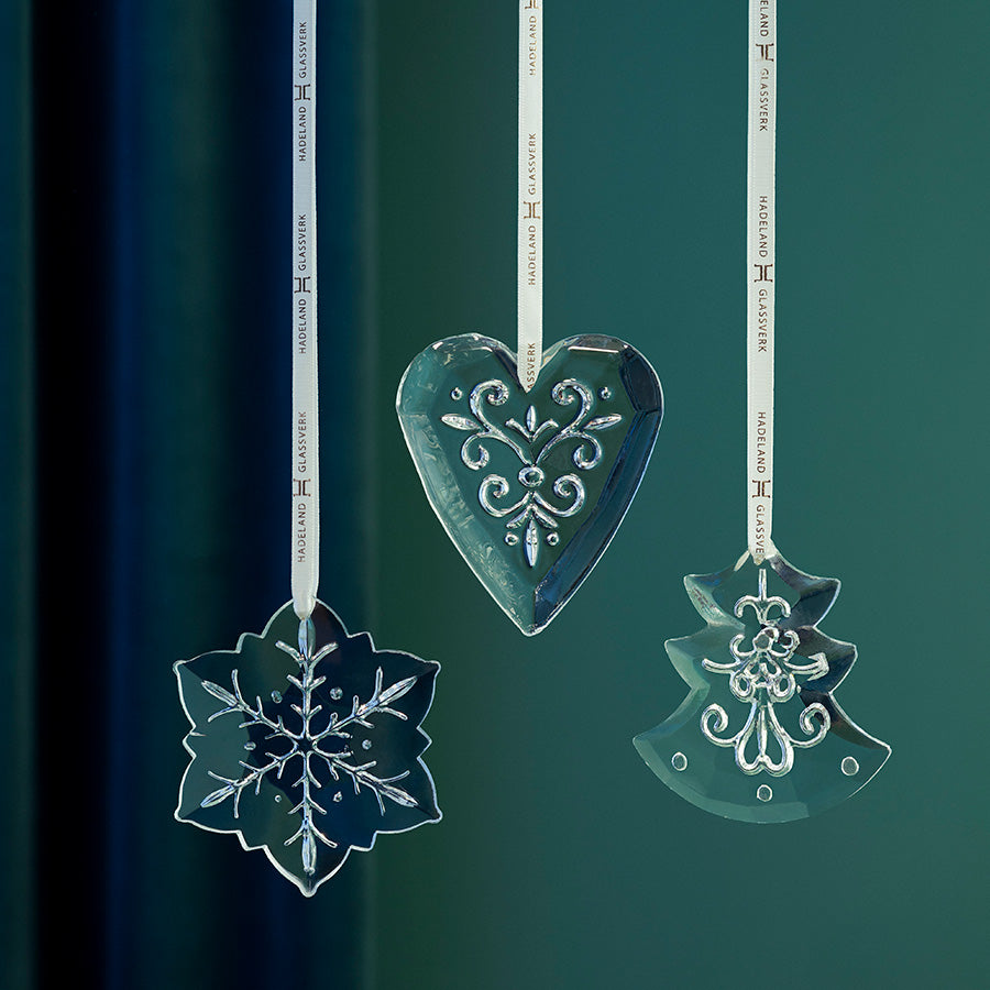 Dekorative ornament i klart glass med inngravert mønster, vist som hjerte, juletre og snøfnugg