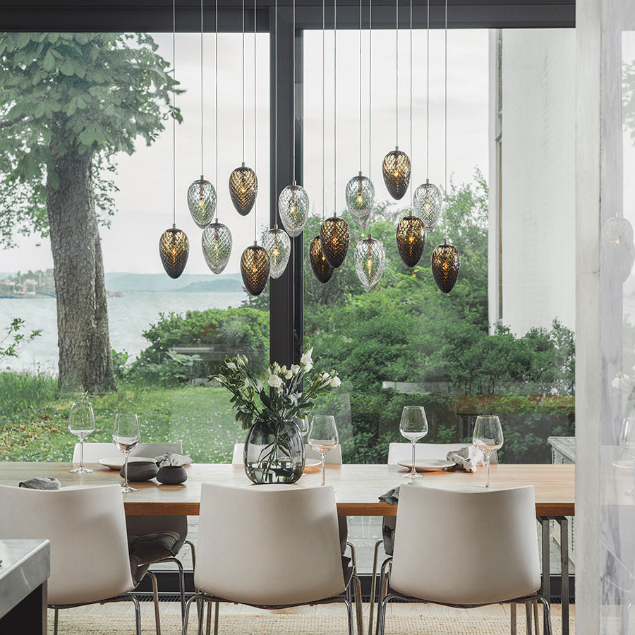 Elegant taklampe i moderne spisestue med femten krystallkongler, som gir et varmt og stilfullt lys over bordet.
