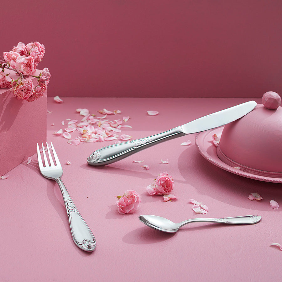 Hardanger Bestikk Nina Spisegaffel fra HARDANGER BESTIKK vist på rosa borddekking med blomster og andre bestikkdeler