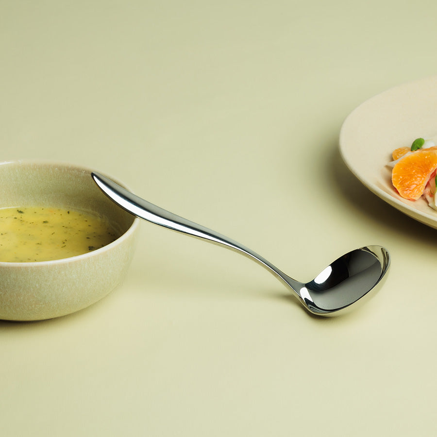 Lykke sauseøse i bruk, plassert ved siden av en skål med saus, fremhever dens buklets og moderne design.
