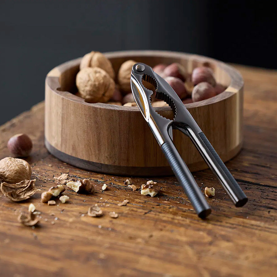 Nøtteknekker i metall ligger i en rund skål med nøtter, ideelt for jule- og høytidsselskap.