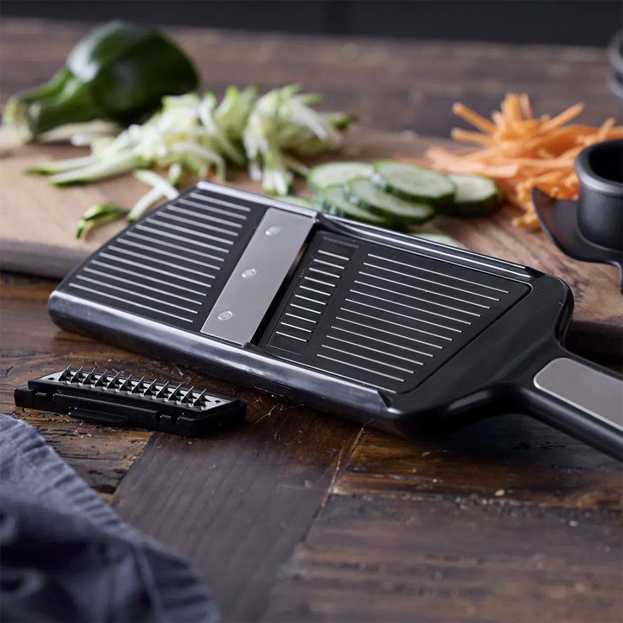 Holm mandolin tilberedes på en kjøkkenbenk med grønnsaker som agurk og gulrot i bakgrunnen.