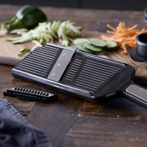 Holm mandolin tilberedes på en kjøkkenbenk med grønnsaker som agurk og gulrot i bakgrunnen.