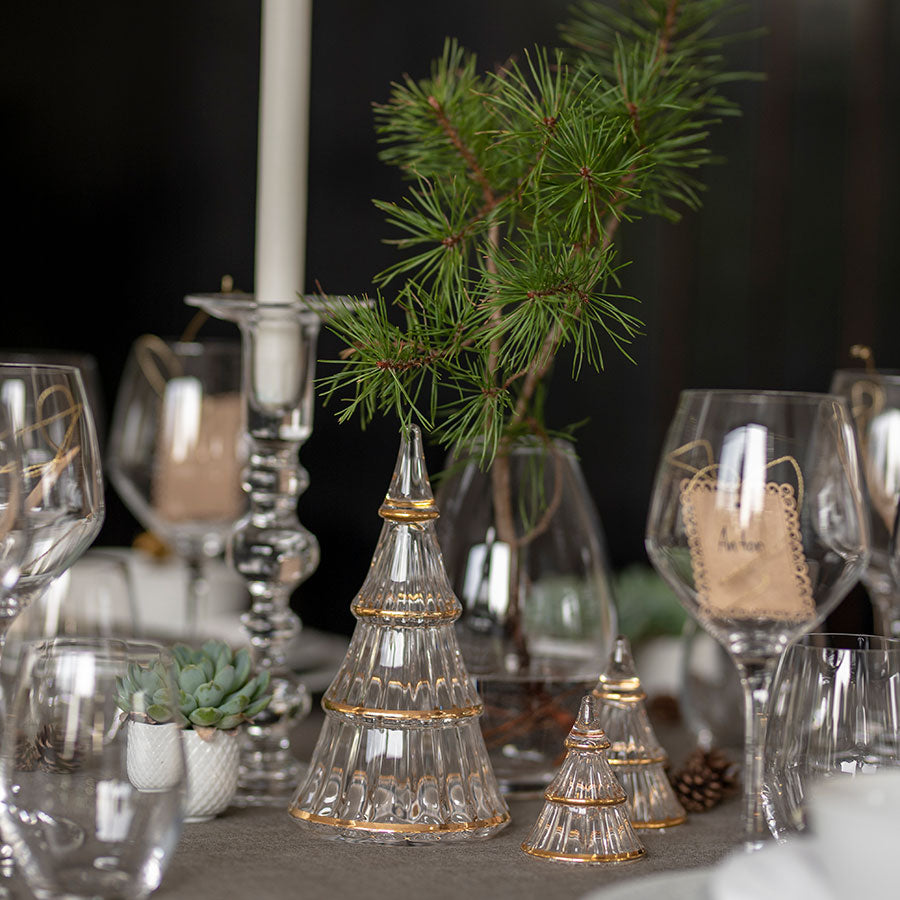 Holmegaard Fairytales juletre i glass på en festdekket julemiddag med lys og grønn pynt, en del av en elegant juledekorasjon.