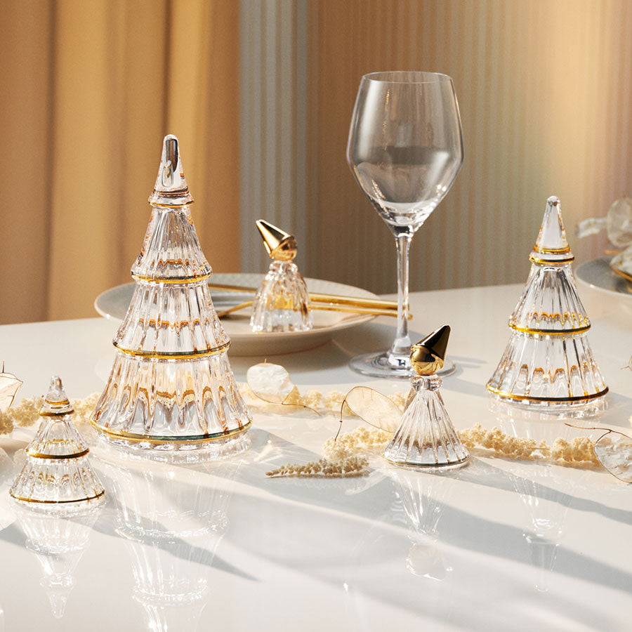 Samling av flere juletre i klart glass med gull detaljer, kombinert med festlig borddekorasjon. Ideell for julefeiring og dekorasjon.