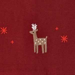 Nærbilde av julerød juleduk med brodert reinsdyr, julestjerner og små julemotiver i naivistisk stil