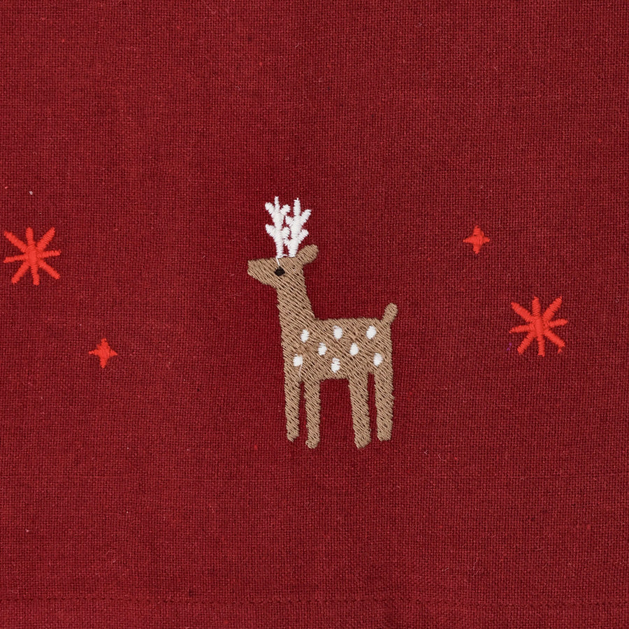 Nærbilde av julerød juleduk med brodert reinsdyr, julestjerner og små julemotiver i naivistisk stil
