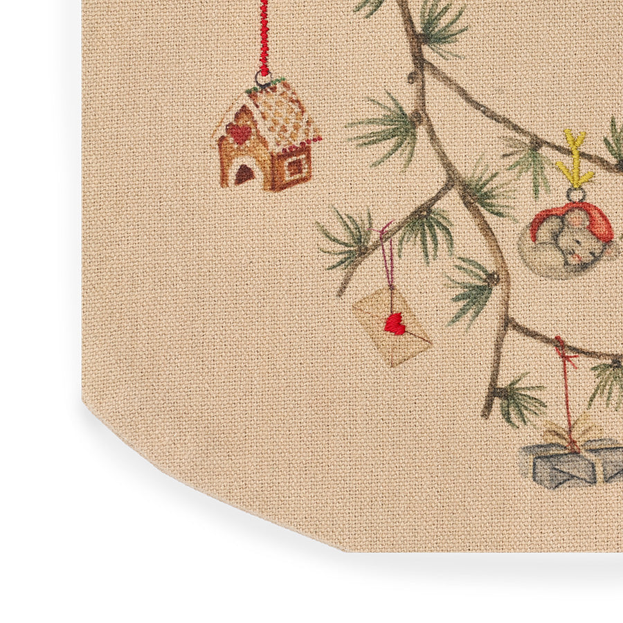 Nærbilde av sandfarget julesokk med detaljerte broderier av julehus, gaver og grangren