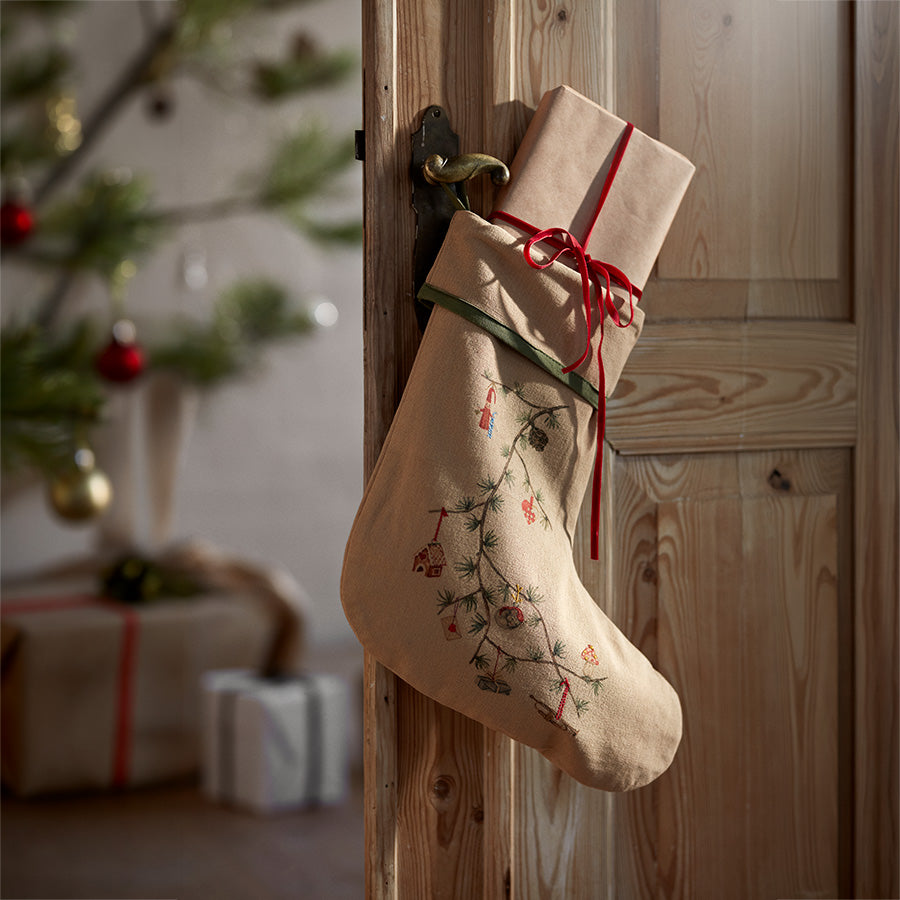 Kähler Hammershøi Christmas julesokk hengt opp med julegave ved juletre og trevegg