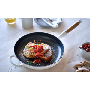 Le Creuset støpejernspanne i bruk, servering av brødskiver med bær.