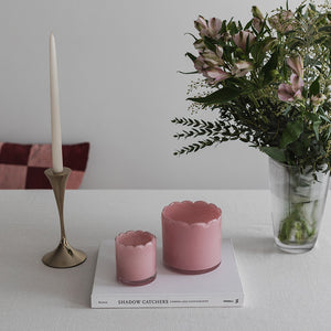 Styling med rosa telysholder i glass på et bord, omgitt av blomster og en stearinlys, som gir et romantisk uttrykk.
