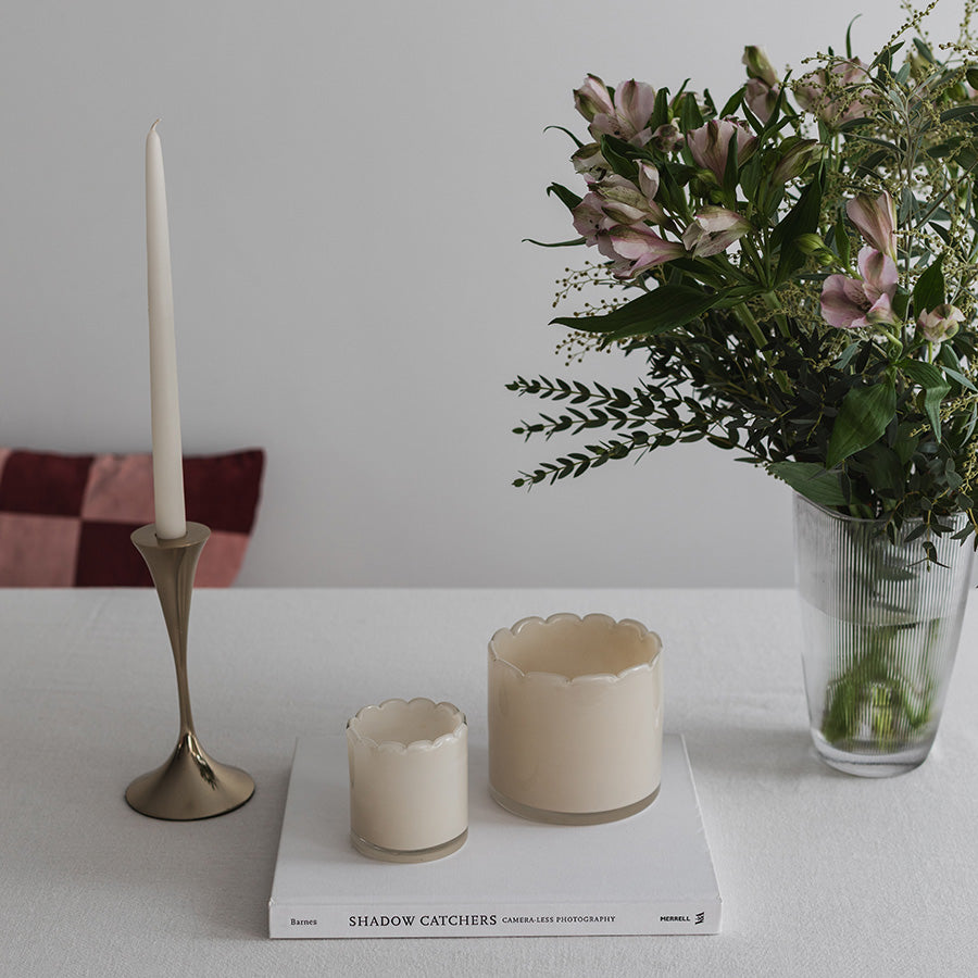 Telysholdere i kremfarge i forskjellige størrelser, dekorert med blomster og bordpynt, gir stil til interiøret.