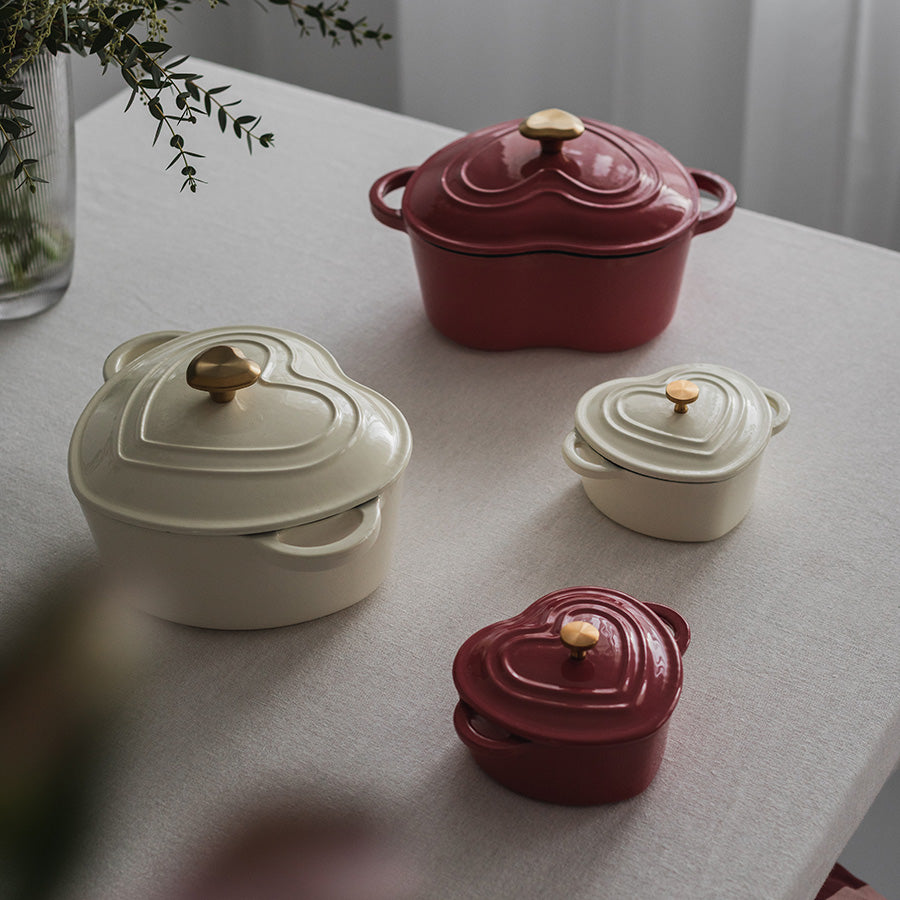 Flere Seasons Love Collection Støpejernsformer i hjerteform, inkludert kremfarget og rød variant, perfekt til porsjonsservering.