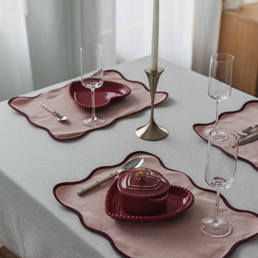 Dekket bord med en bringebær-rød støpejernsform i hjerteform, elegant presentert med champagneglass og pynt.