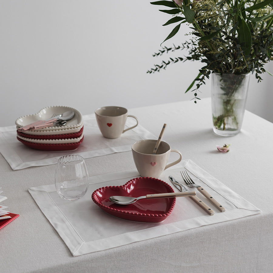 Seasons love Collection Tallerken Hjerte Bringebær Rød 20cm - Hjerteformet tallerken kombinert med kremfargede krus og bestikk på dekket bord.